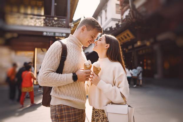 newlywed couple eating ice cream from a cone on a street in Shanghai near Yuyuan China.