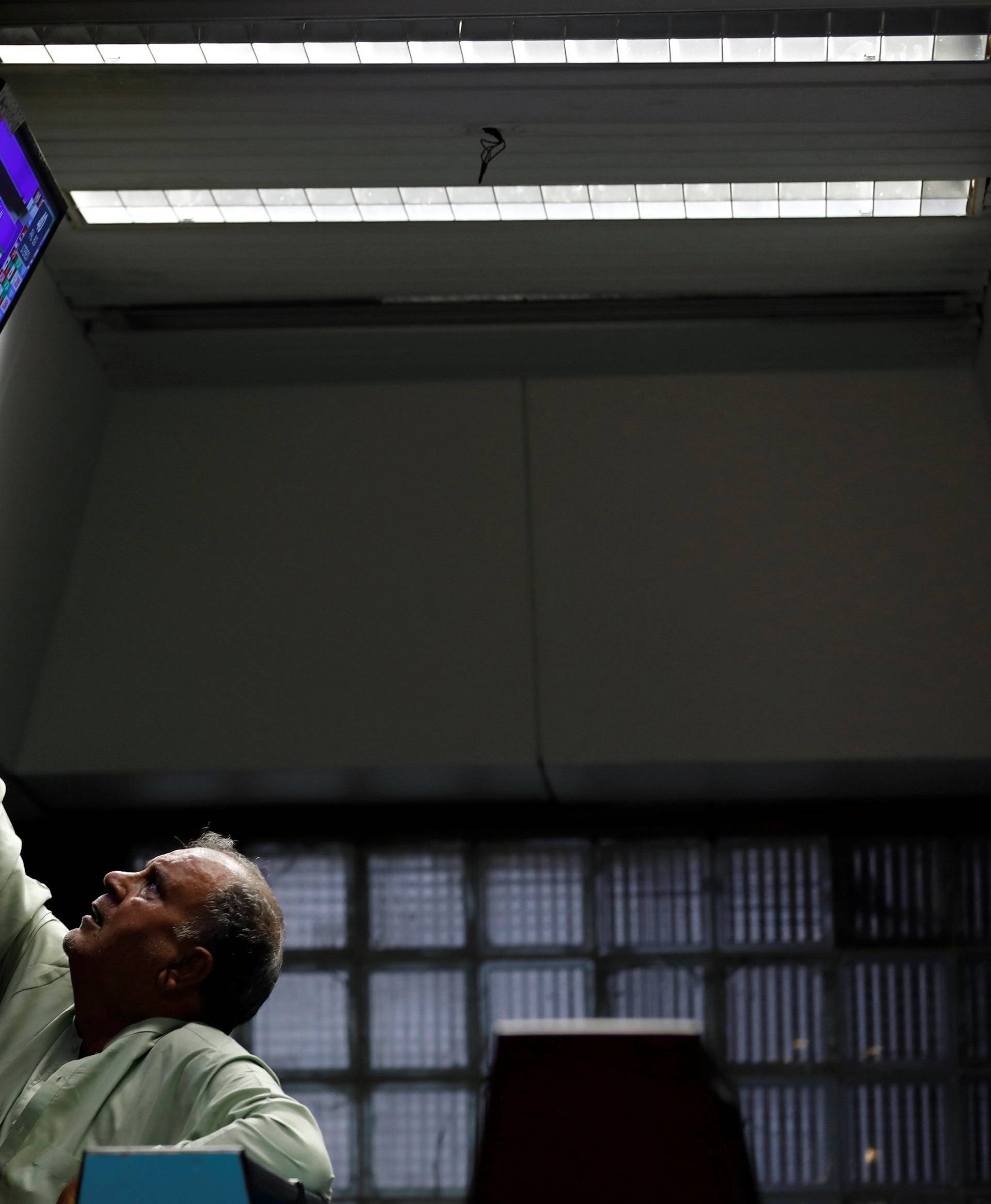 A broker tunes television set, displaying the unofficial results of yesterdayÃs general election, during trading session at the Pakistan Stock Exchange, in Karachi