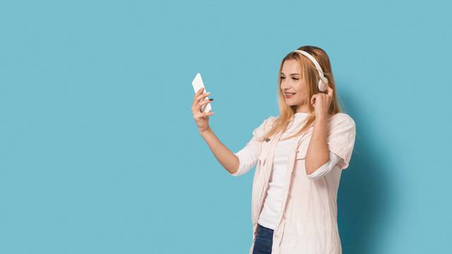 Smiling girl looks at her smartphone while listening to the music