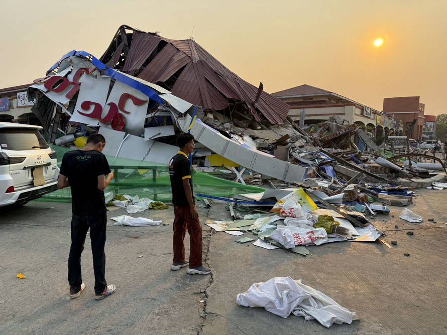 People stand near a commercial facility which collapsed due to an earthquake, in Naypyitaw