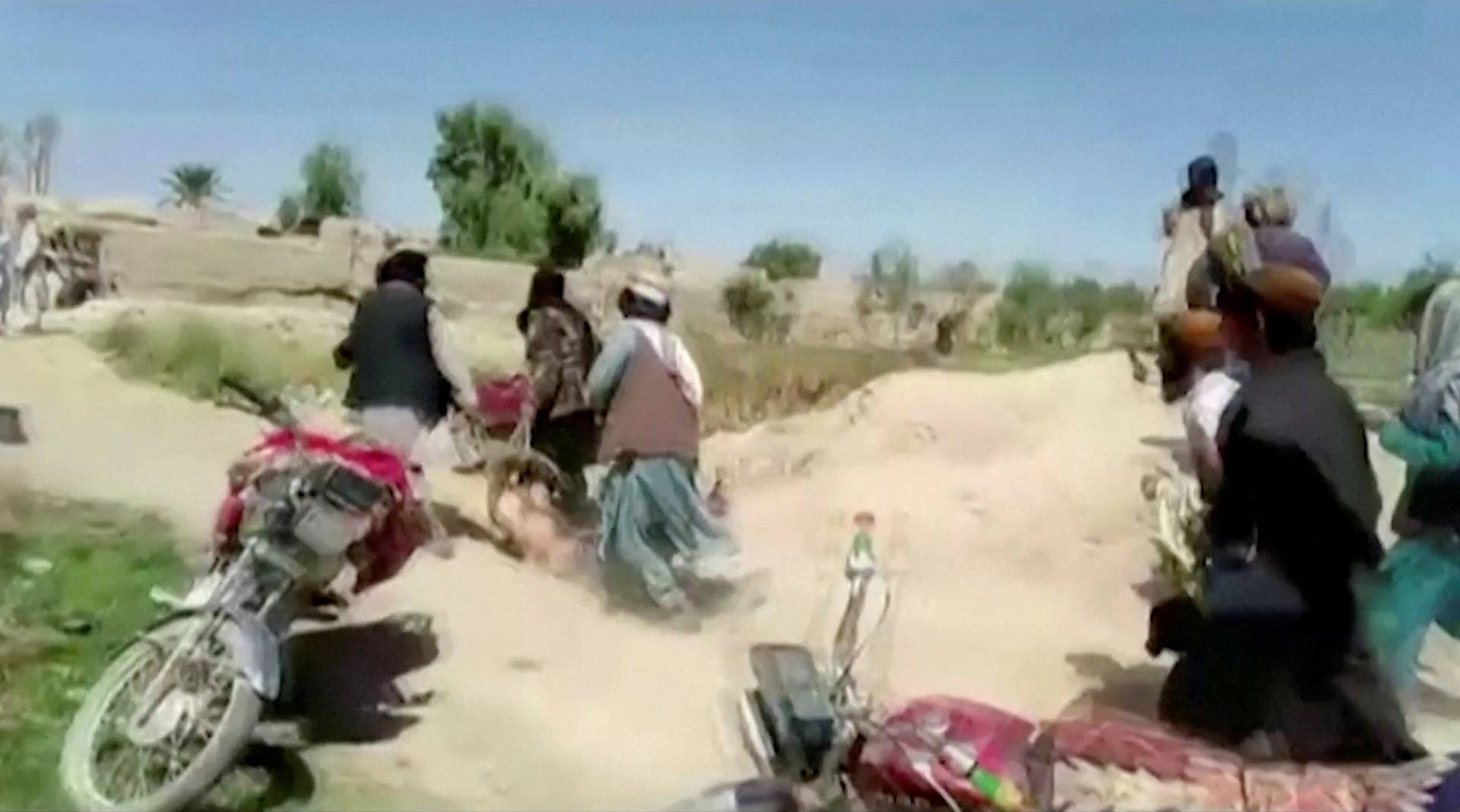 Men said to be Taliban fighters drag the body of a man on the ground at a location said to be Farah