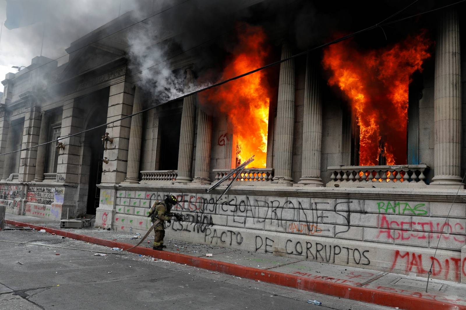 A firefighter works on the Congress building, set on fire by demonstrators during a protest demanding the resignation of President Alejandro Giammattei, in Guatemala City