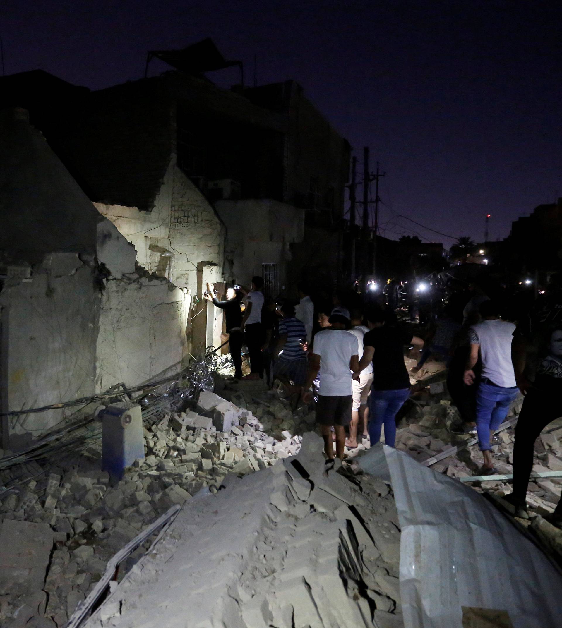 Civilians inspect the site of a car bomb attack in Sadr City district of Baghdad