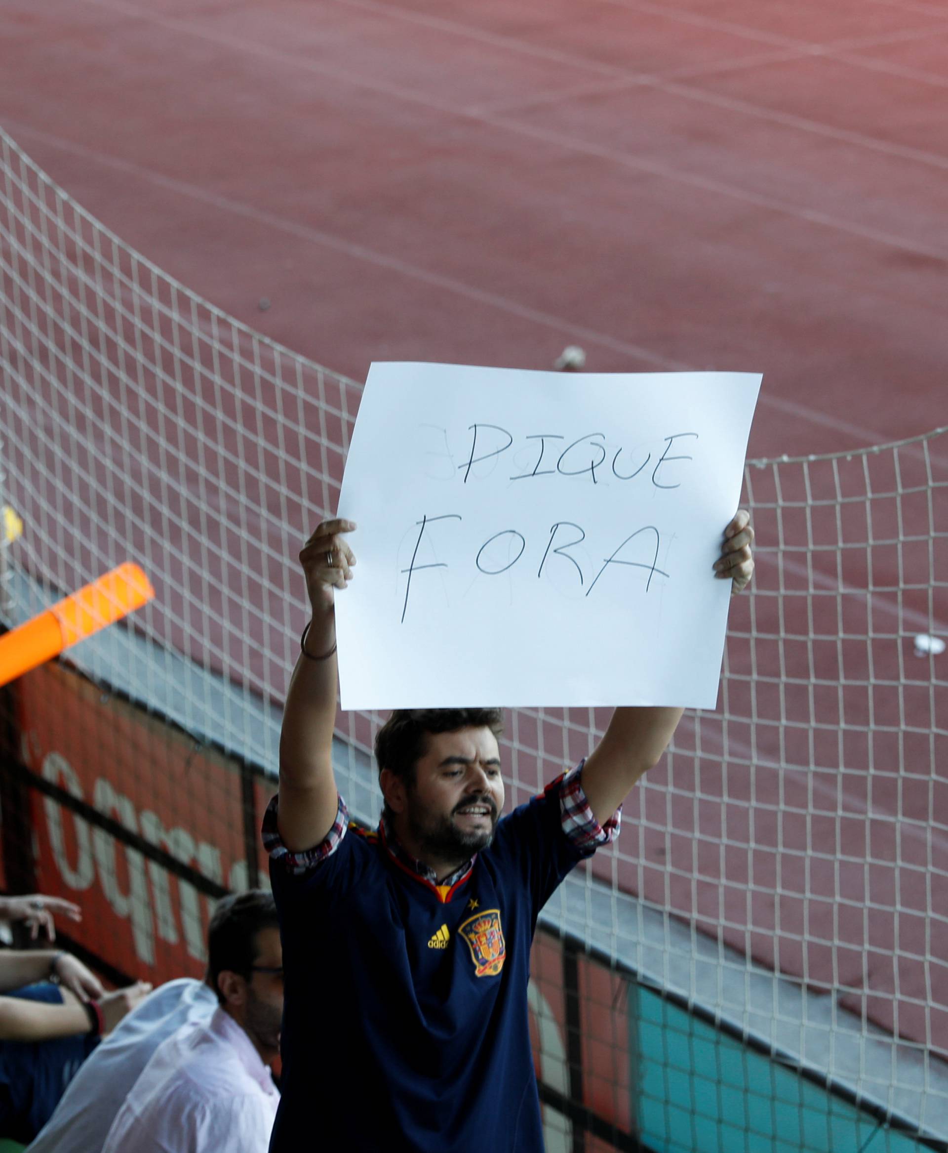 A man displays a banner that reads "Pique Out", referring to Spain's player Gerard Pique, before a training session in Las Rozas, near Madrid