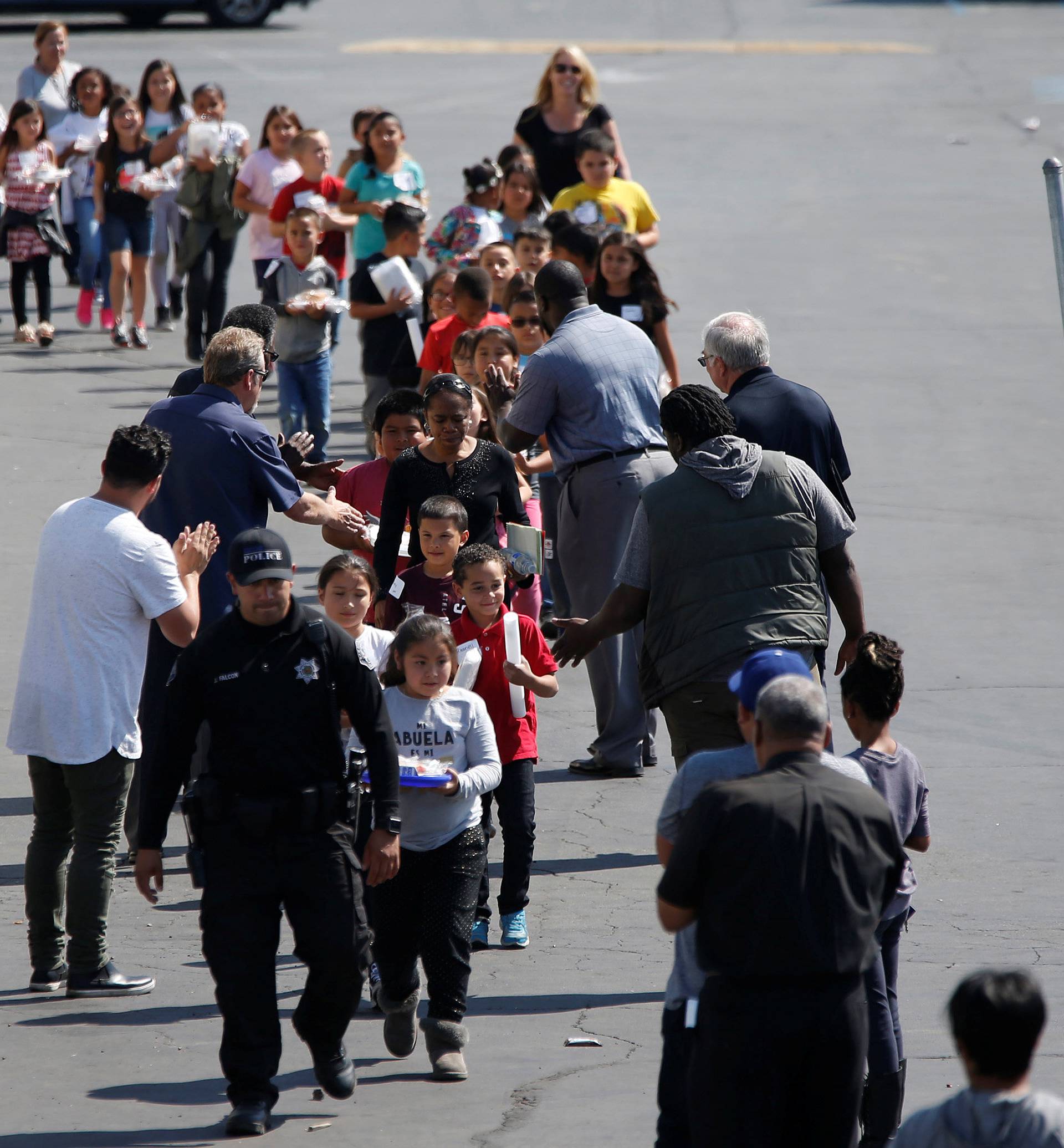 Students who were evacuated after a shooting at North Park Elementary School walk past well-wishers to be reunited with their waiting parents at a high school in San Bernardino
