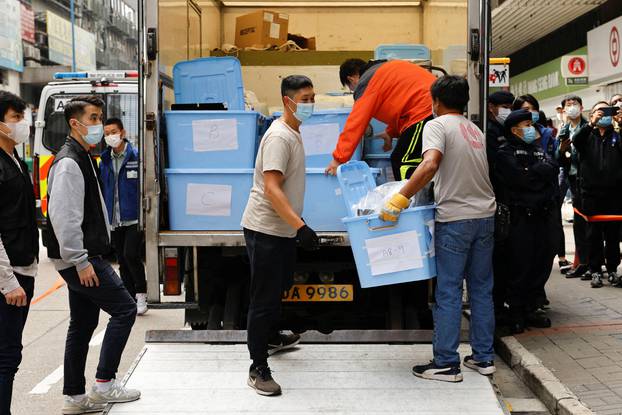 Movers collect boxes of evidence after a police search at the office of Stand News, in Hong Kong