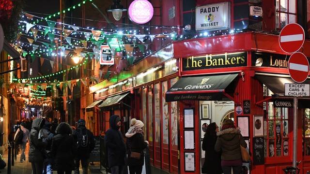 People walk under Christmas lights illuminating a street in Dublin