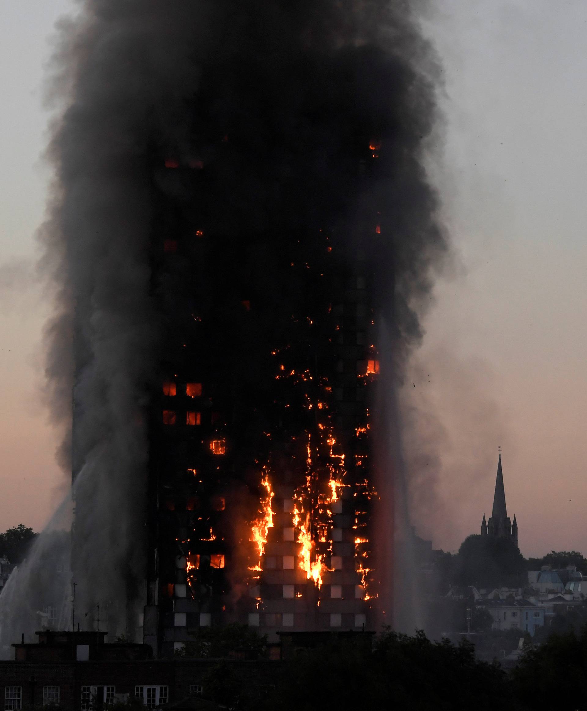 Flames and smoke billow as firefighters deal with a serious fire in the Grenfell Tower apartment block at Latimer Road in West London