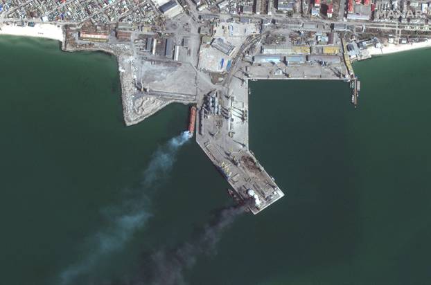A satellite image shows an overview of a capsized ship and a burning storage tank, at the port of Berdiansk