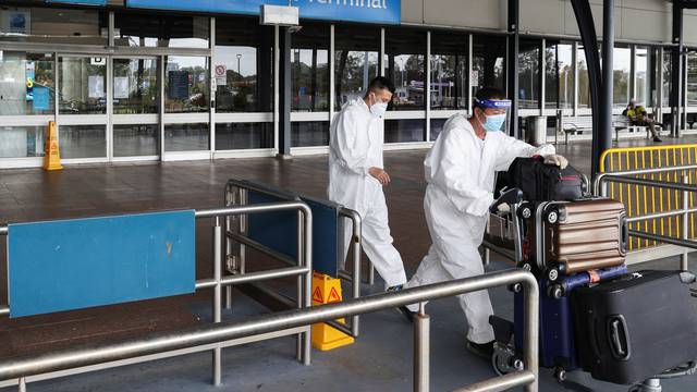 Travellers wear personal protective equipment outside the international terminal at Sydney Airport in Sydney