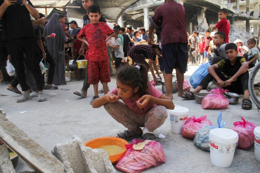 FILE PHOTO: Palestinians gather to receive food cooked by a charity kitchen, amid Israel-Hamas conflict, in Jabalia
