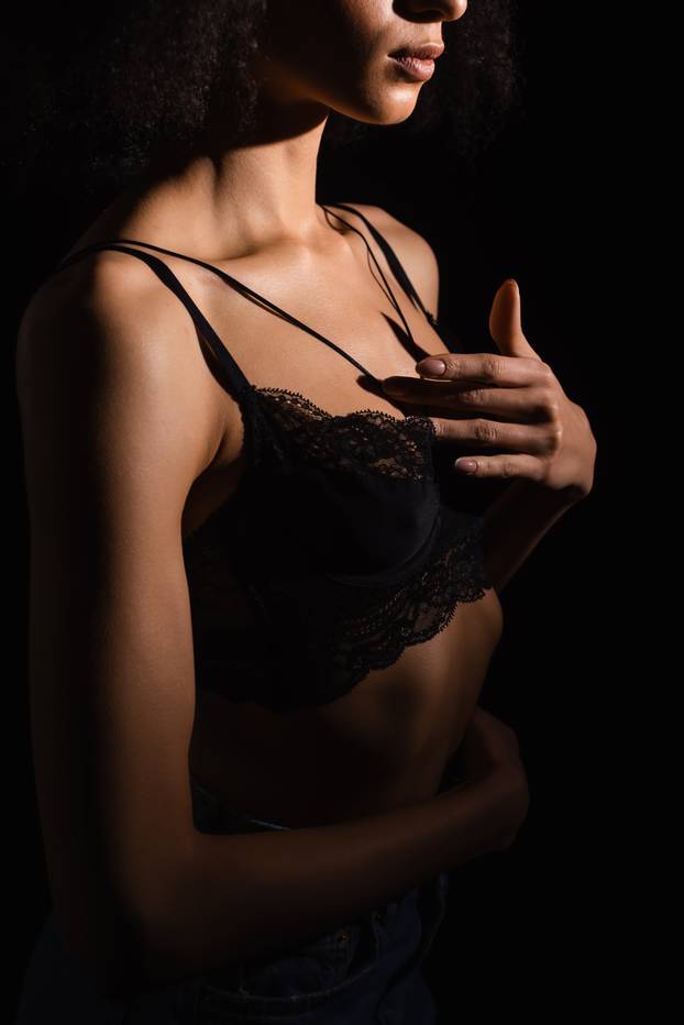 Cropped view of african american woman in bra touching chest isolated on black