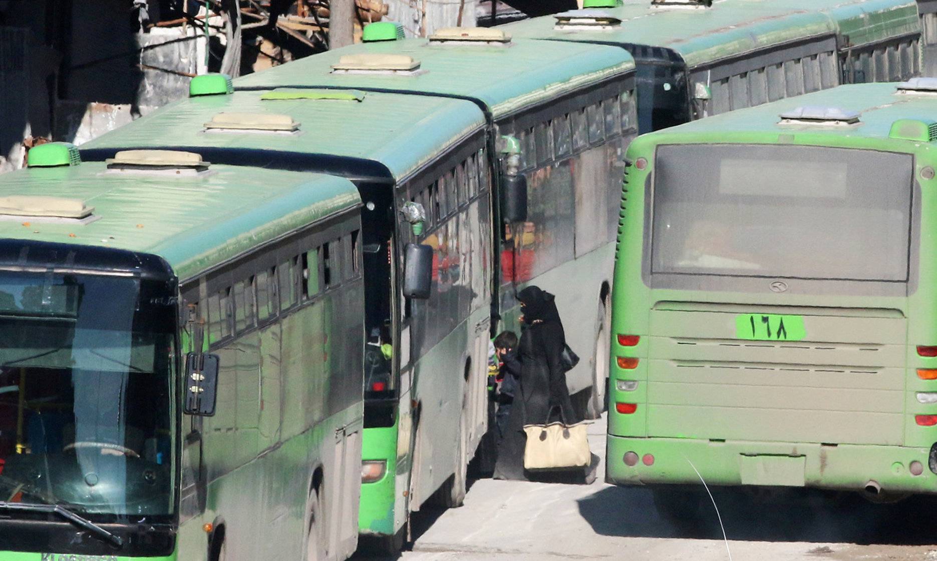 People get on buses to be evacuated from al-Sukkari rebel-held sector of eastern Aleppo