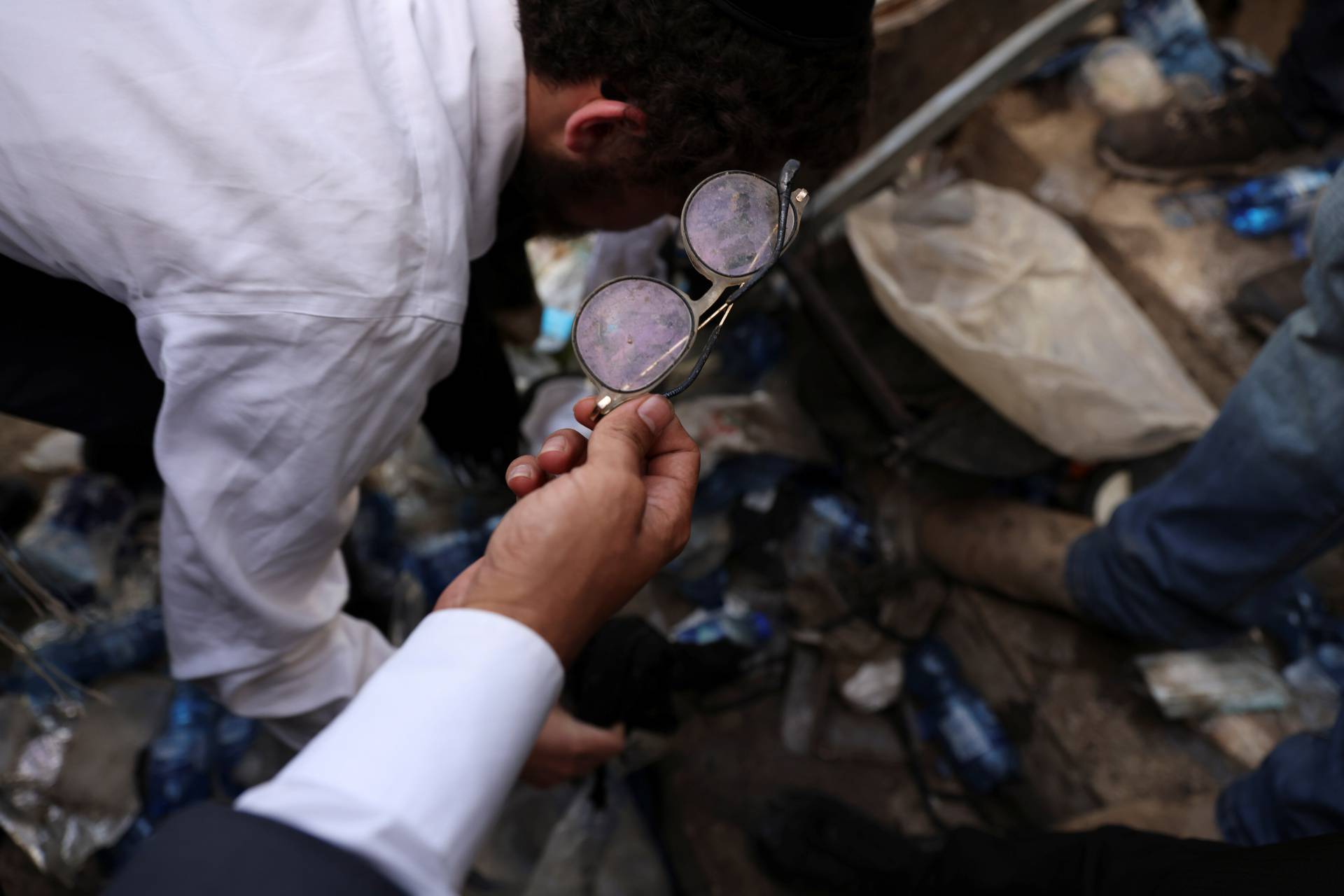 A man holds a left over glasses on Mount Meron