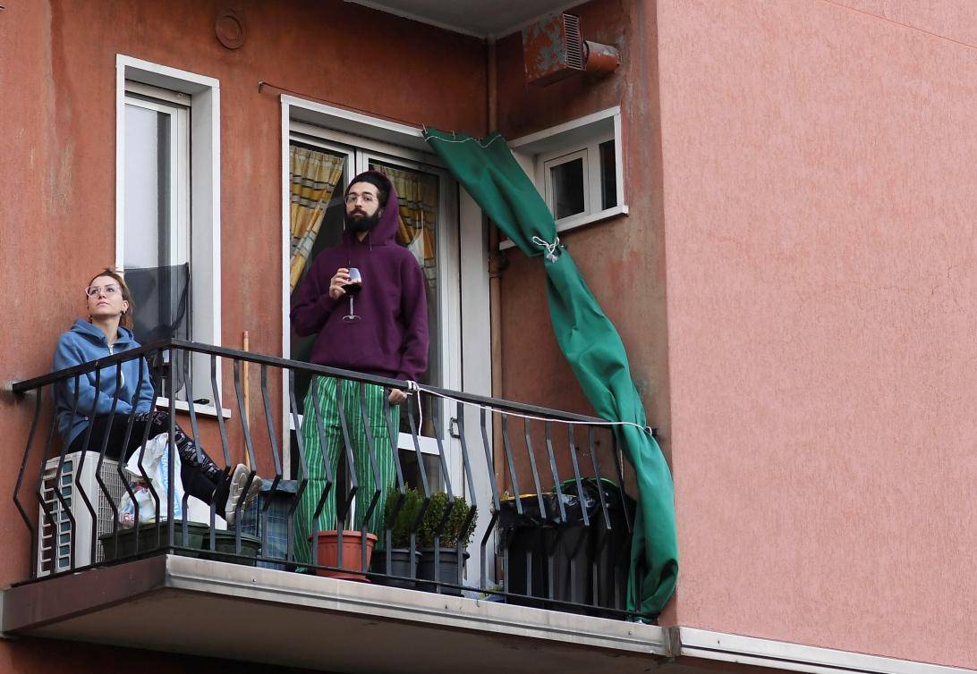 A man listens as a neighbor plays the guitar from a balcony to raise morale on the sixth day of an unprecedented lockdown across of all Italy imposed to slow the outbreak of coronavirus in Milan