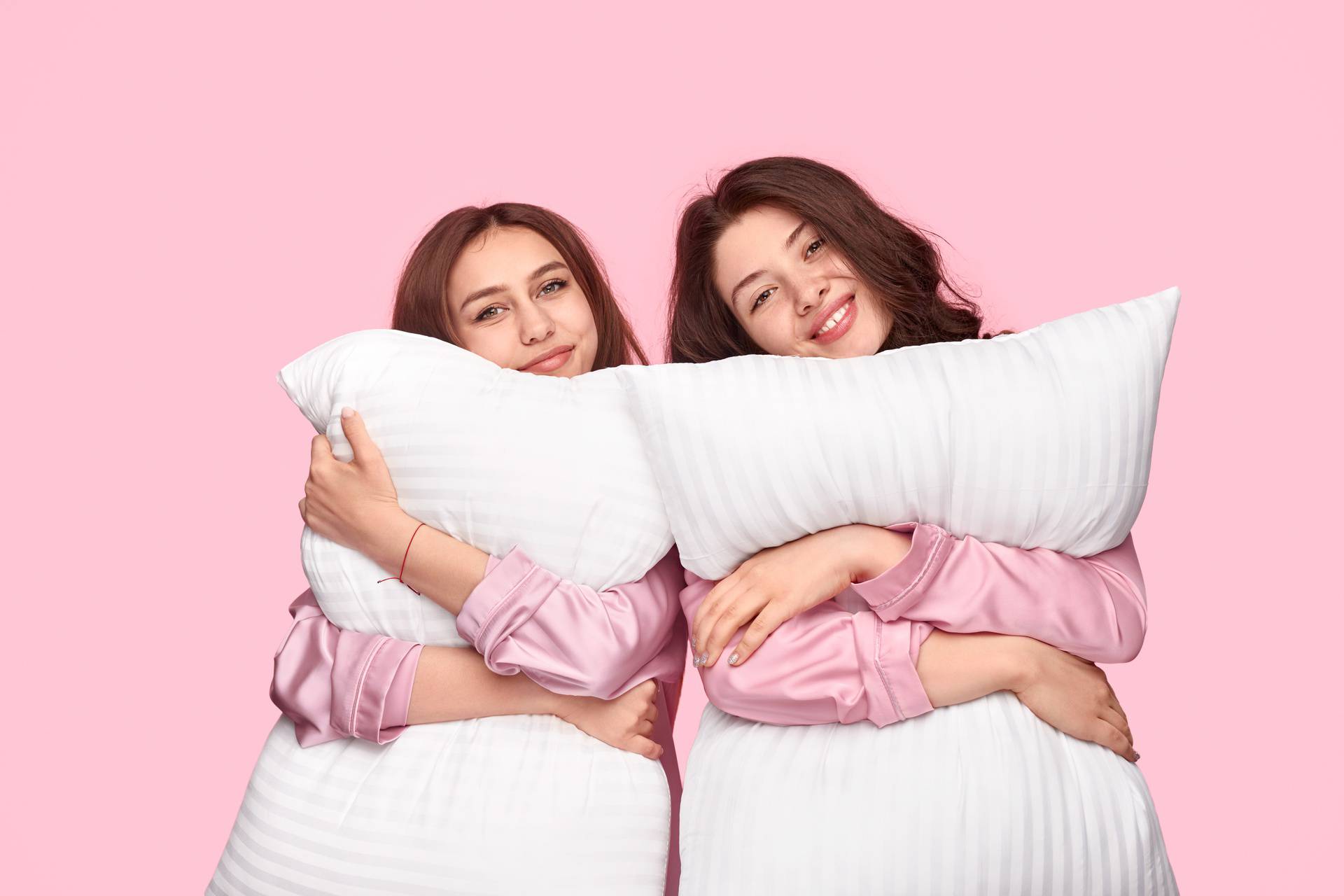 Young women hugging soft pillows during sleepover