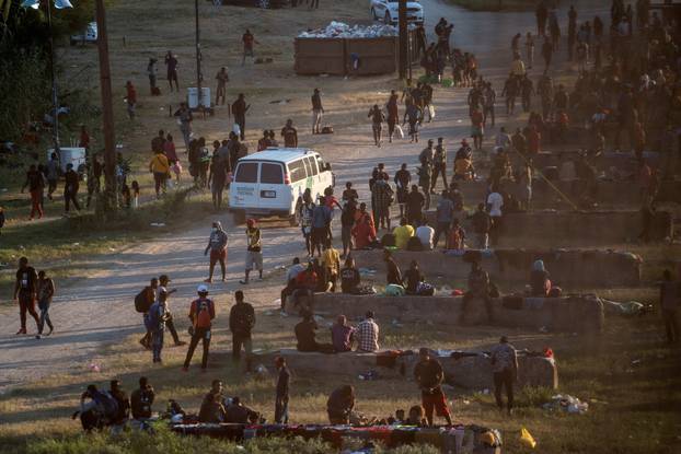 Migrants seeking asylum in the U.S. wait to be processed under the International Bridge in Del Rio