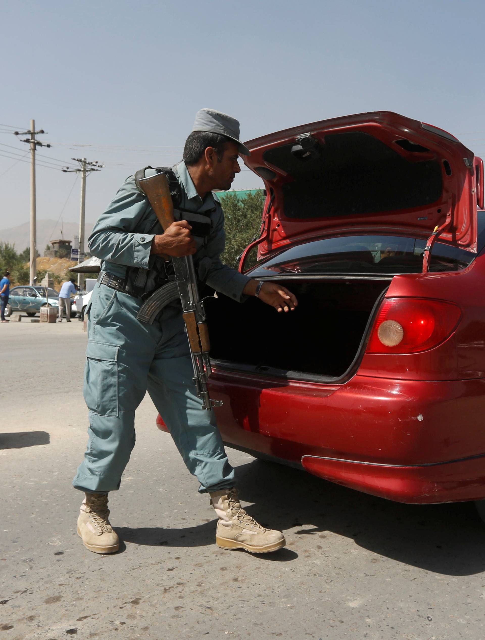 An Afghan policeman inspects a car at a checkpoint near the site of kidnapping in Kabul 