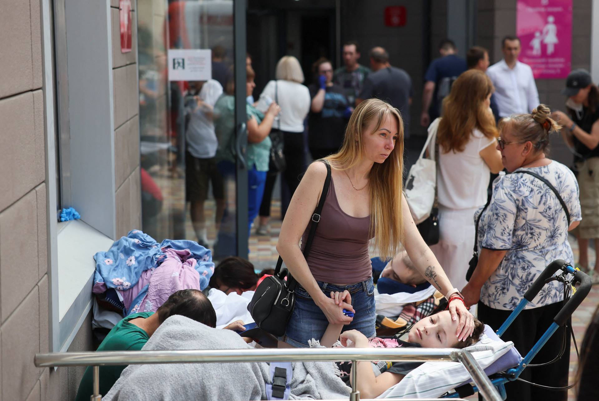 A woman touches a patient near Ohmatdyt Children's Hospital that was damaged during Russian missile strikes, in Kyiv