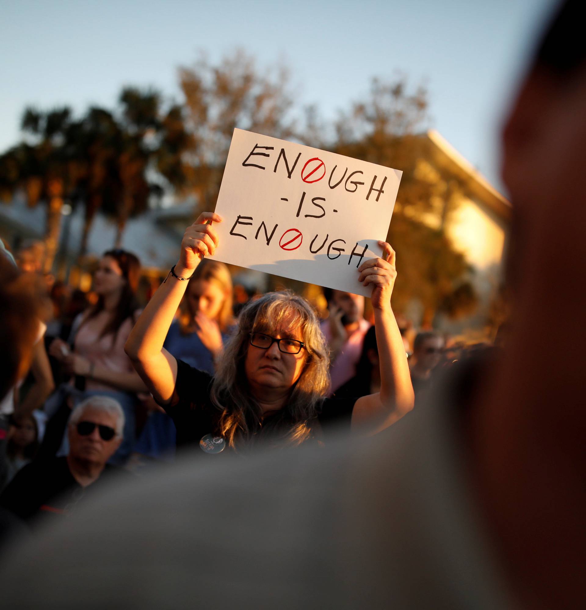 A woman holds a placard during a candlelight vigil for victims of yesterday's shooting at nearby Marjory Stoneman Douglas High School, in Parkland