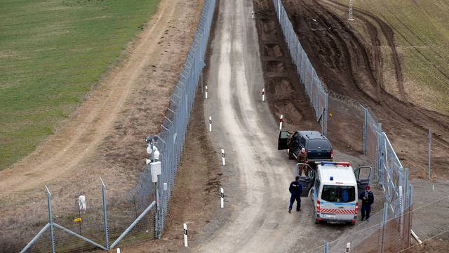 A Hungarian police and soldiers patrol the Hungary-Serbia border, which was recently fortified by a second fence, near the village of Gara