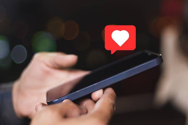 Hand holding smartphone with heart sign. Like symbols appear ove