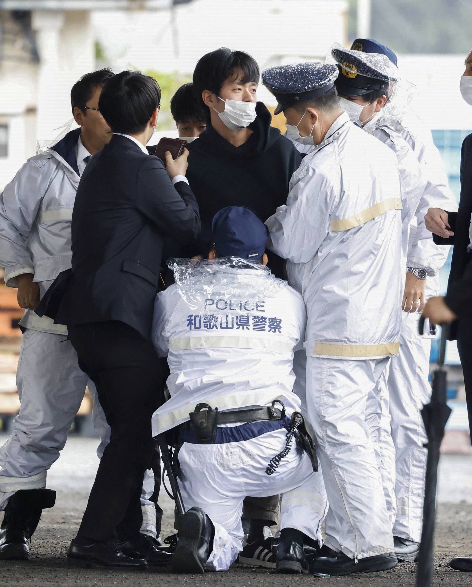 A man, believed to be a suspect who threw a pipe-like object near Japanese Prime Minister Fumio Kishida during his outdoor speech, is held by police officers in Wakayama