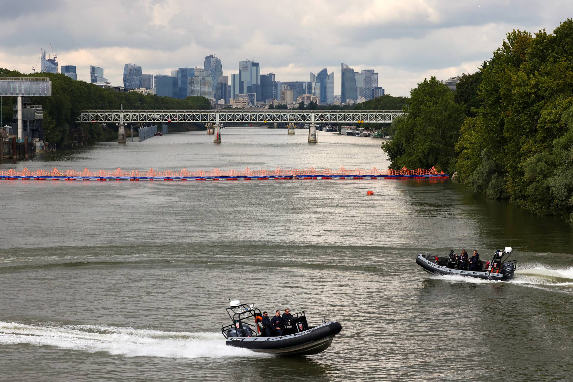 CRS police speedboats patrol on the River Seine near a floating barrier