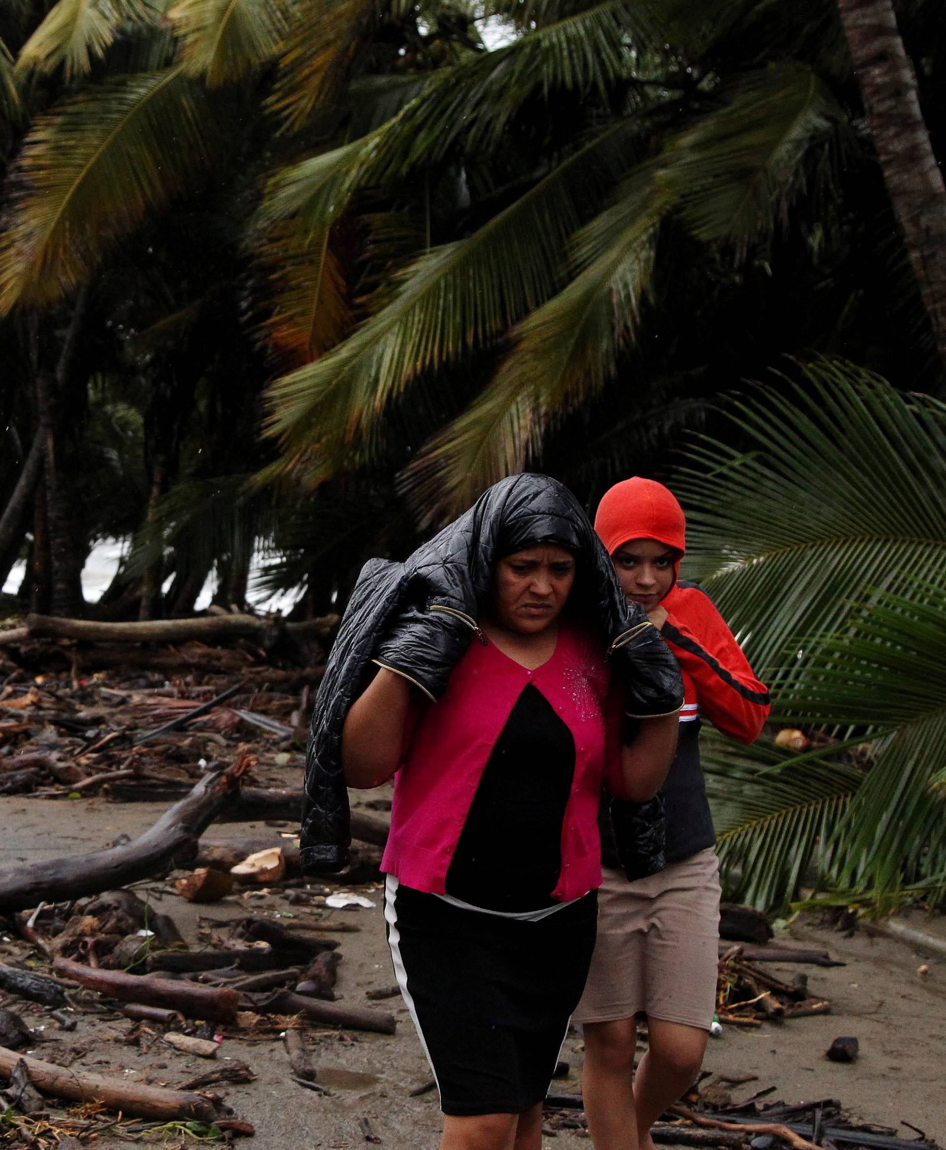 Locals walk along a street near debris as Hurricane Irma moves off the northern coast of the Dominican Republic, in Nagua