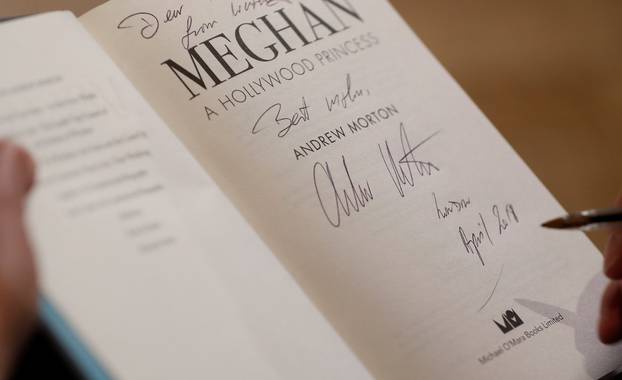 Royal biographer Andrew Morton signs a copy of his latest book, a biography of Meghan Markle, following an interview with Reuters journalists in London