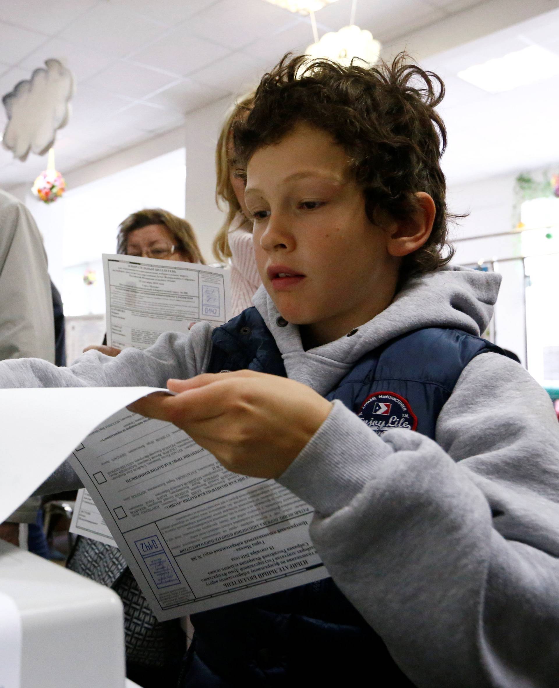 Boy casts ballot during parliamentary election in Moscow