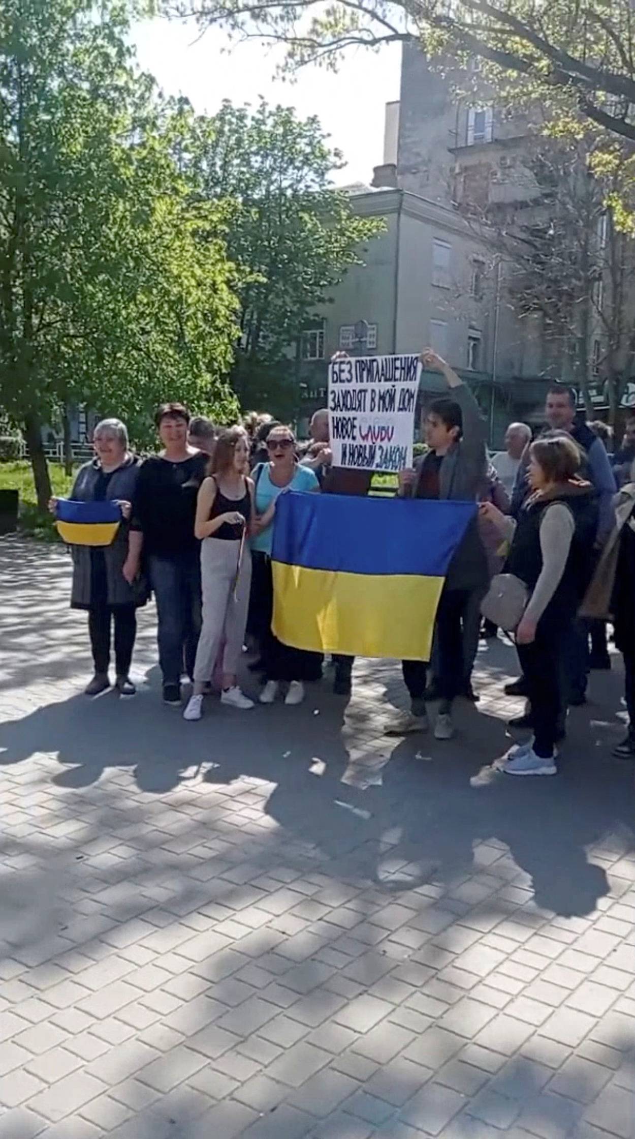 People hold a placard and the Ukraine's national flag during a protest, amid Russia's invasion of Ukraine, in Kherson