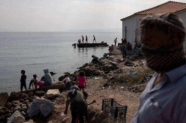 Refugees and migrants from the destroyed Moria camp are seen on a beach near a new temporary camp, on the island of Lesbos