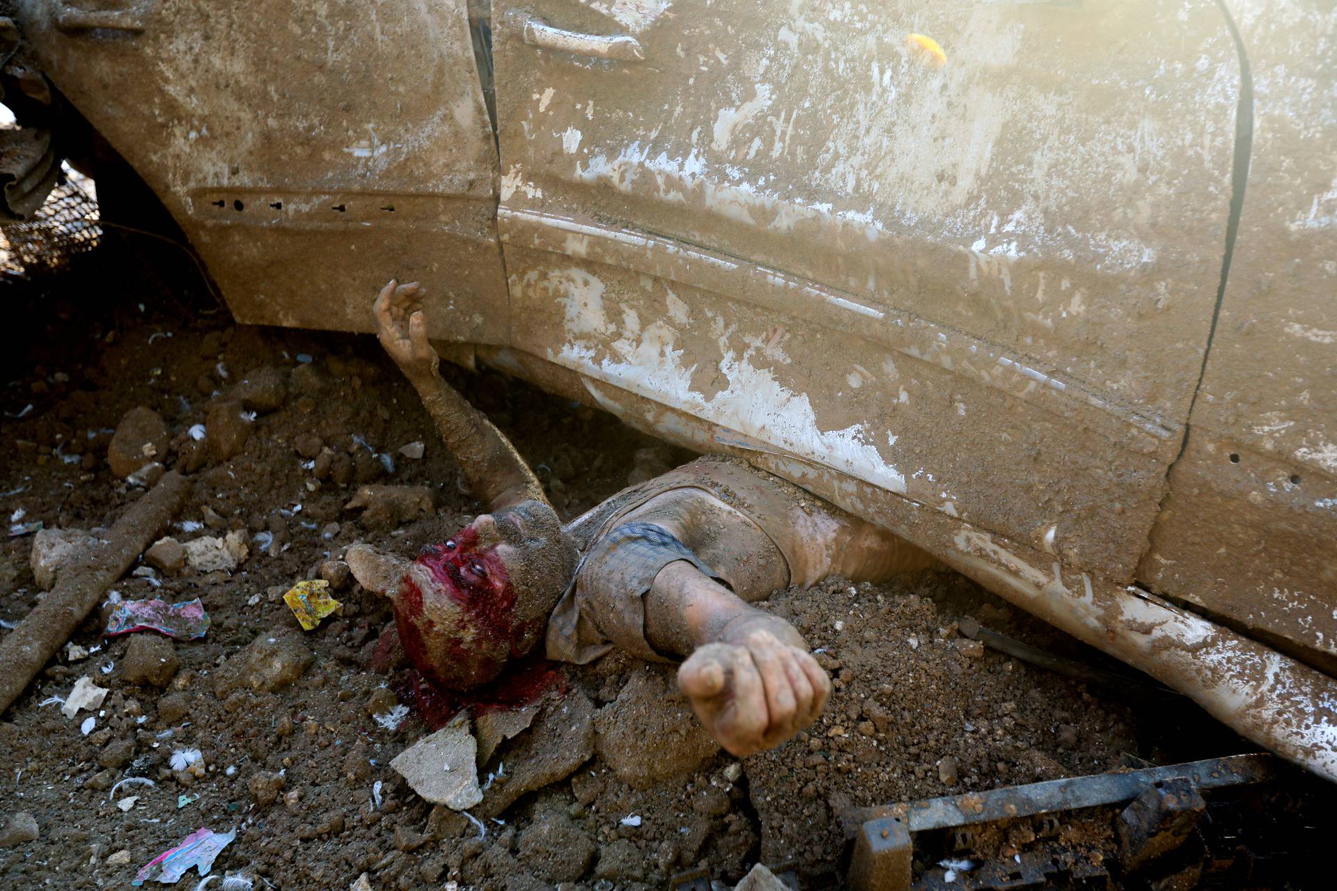 An injured man is pictured under a vehicle following an explosion in Beirut's port area