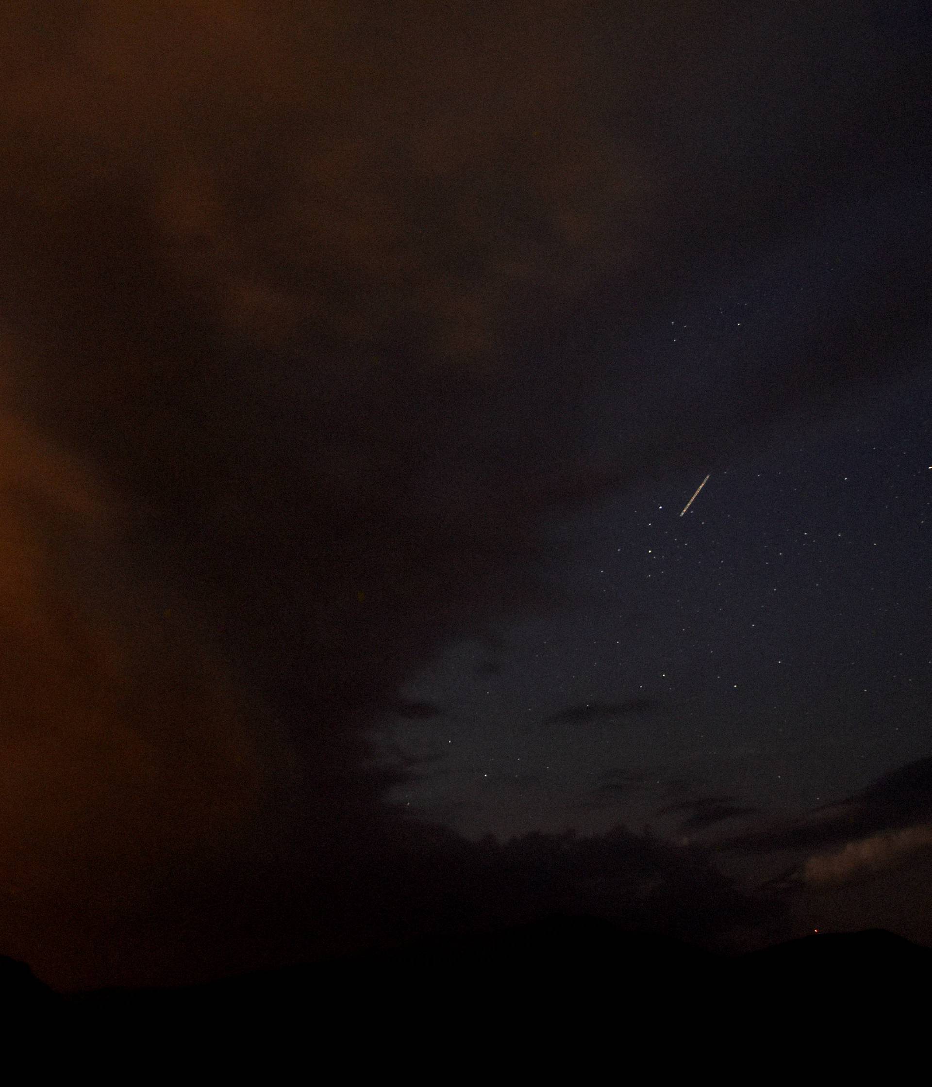 A meteor streaks past stars in cloudy night sky during the annual Perseid meteor shower, near Skopje, Macedonia