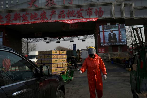 Worker in protective suit holds a thermometer as he checks cars entering the Xinfadi wholesale market, as the country is hit by an outbreak of the novel coronavirus disease (COVID-19), in Beijing