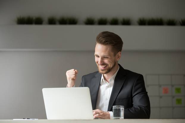 Happy,Young,Businessman,In,Suit,Looking,At,Laptop,Excited,By