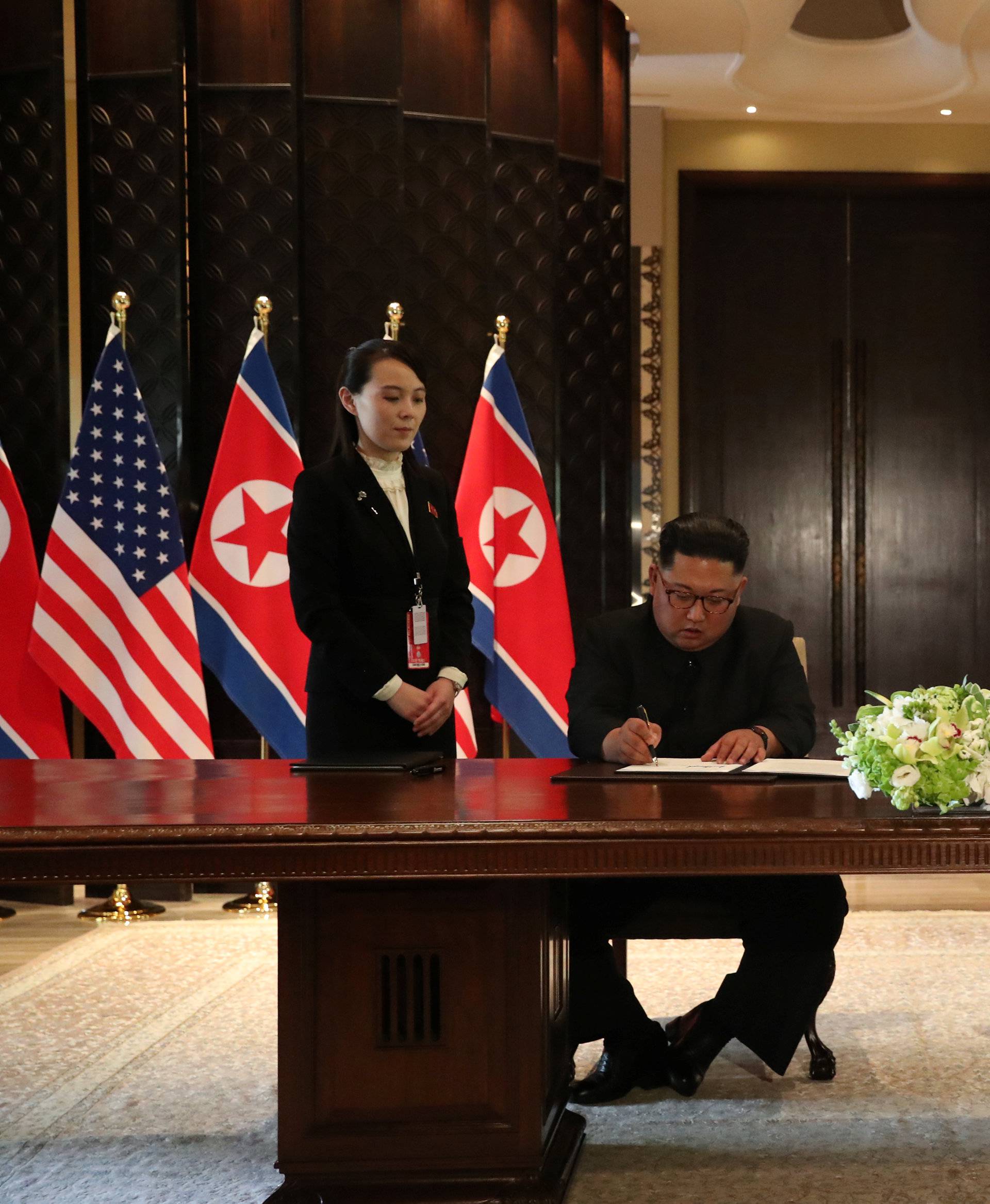 U.S. President Donald Trump and North Korea's leader Kim Jong Un sign documents, after their summit in Singapore