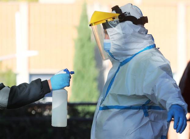 An ambulance worker wearing a full personal protective equipment (PPE) is disinfected by a collage in Leganes