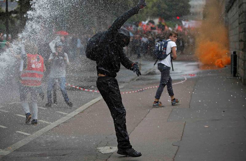 Masked protesters clash with French riot police as they take part in a march in Nantes