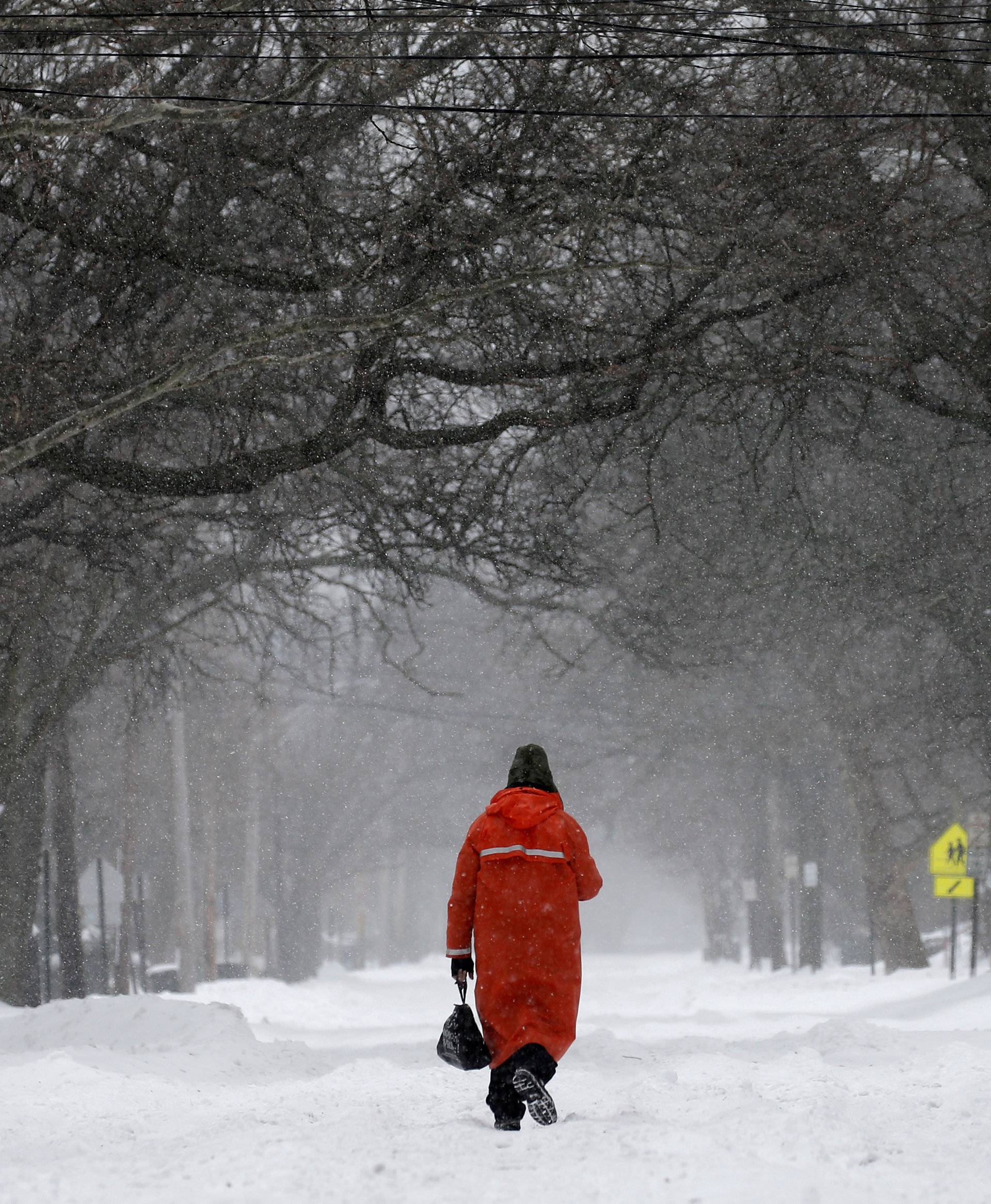 A man walks in the center of a snow covered Broadway during a snowstorm in the village of Nyack