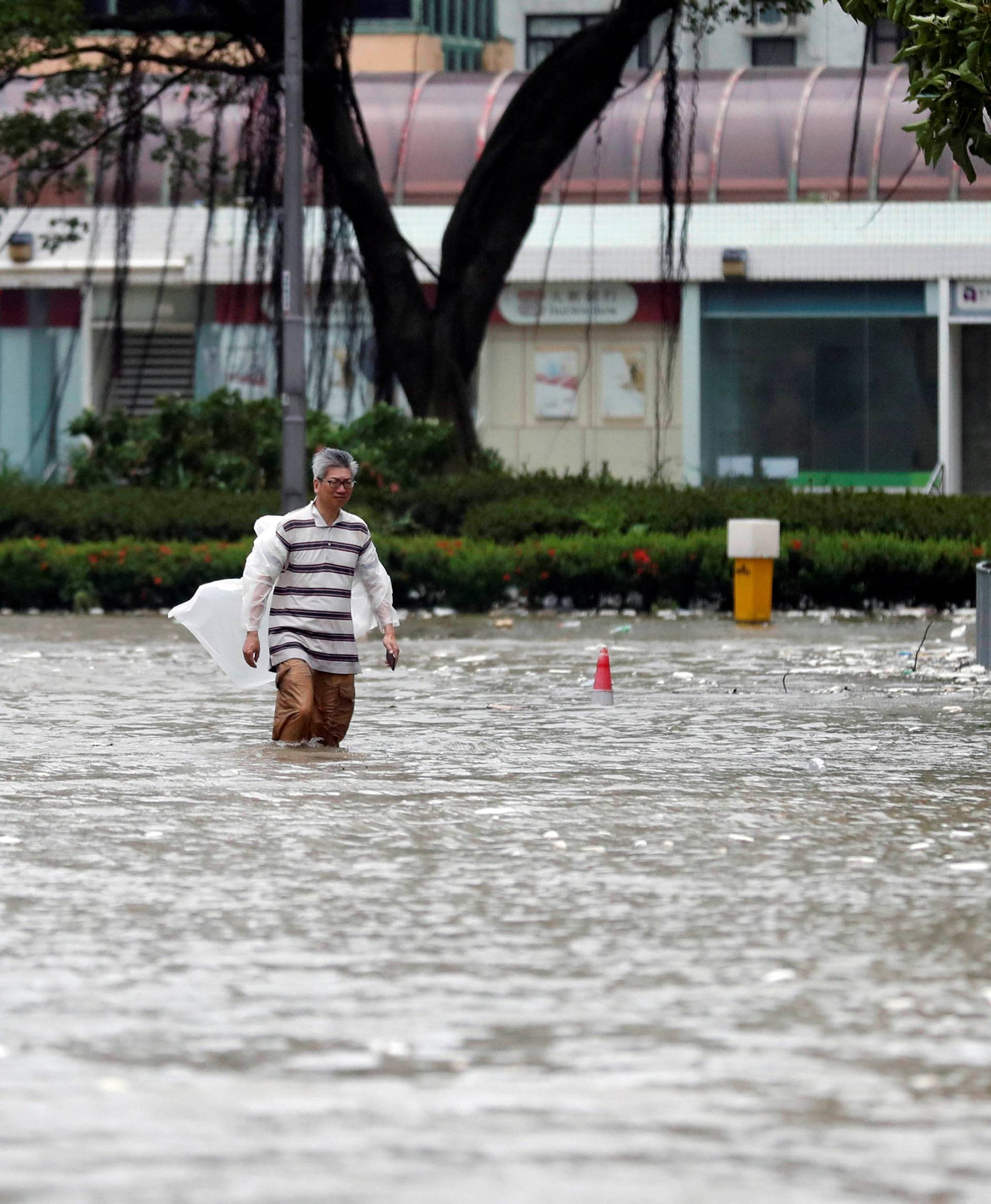 A man walks through a flooded street as Typhoon Hato hits Hong Kong