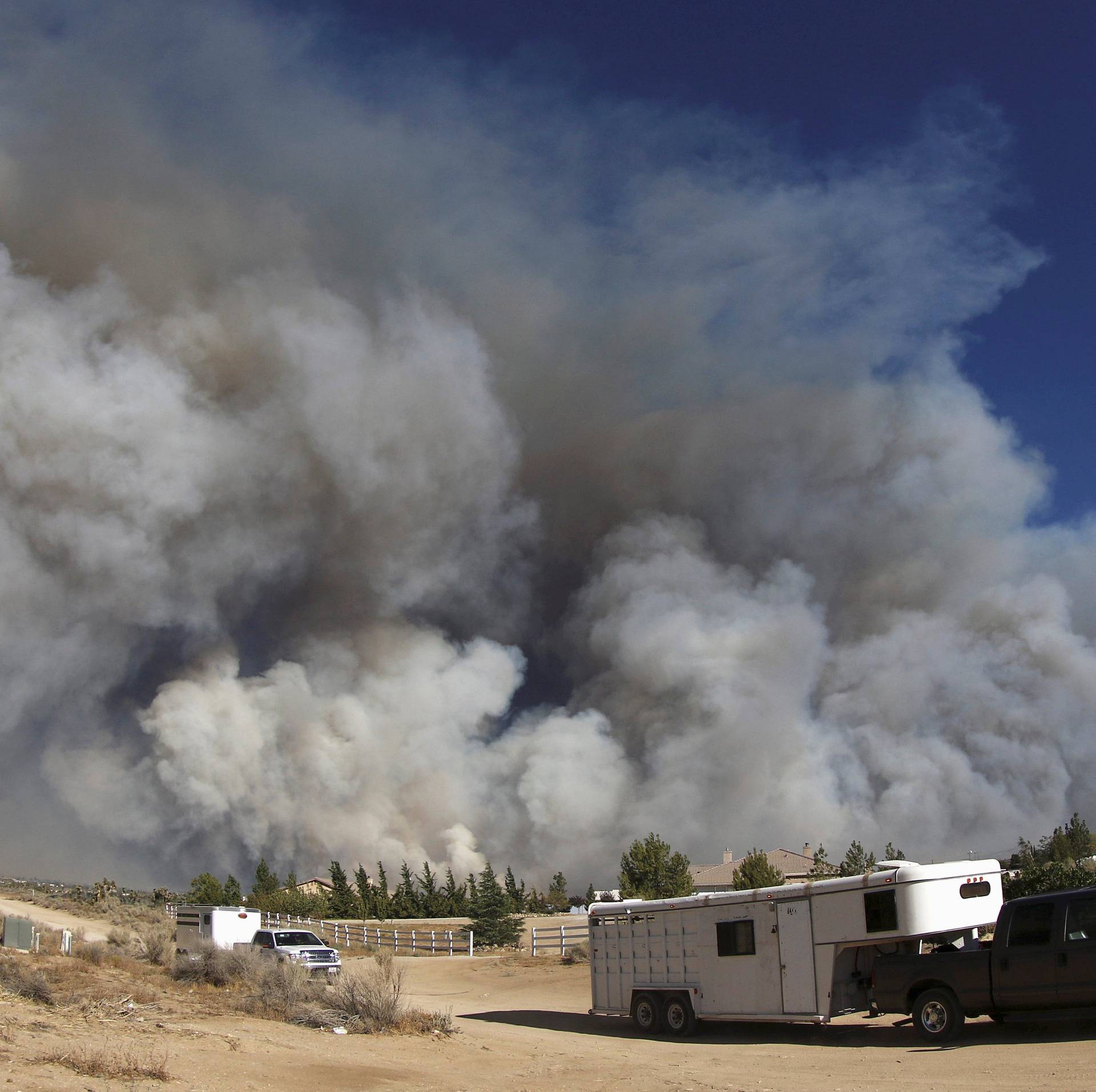People evacuate their horses as smoke fills the skies in this photo taken with an extreme wide angle lens at the so-called Bluecut Fire in San Bernardino County, California