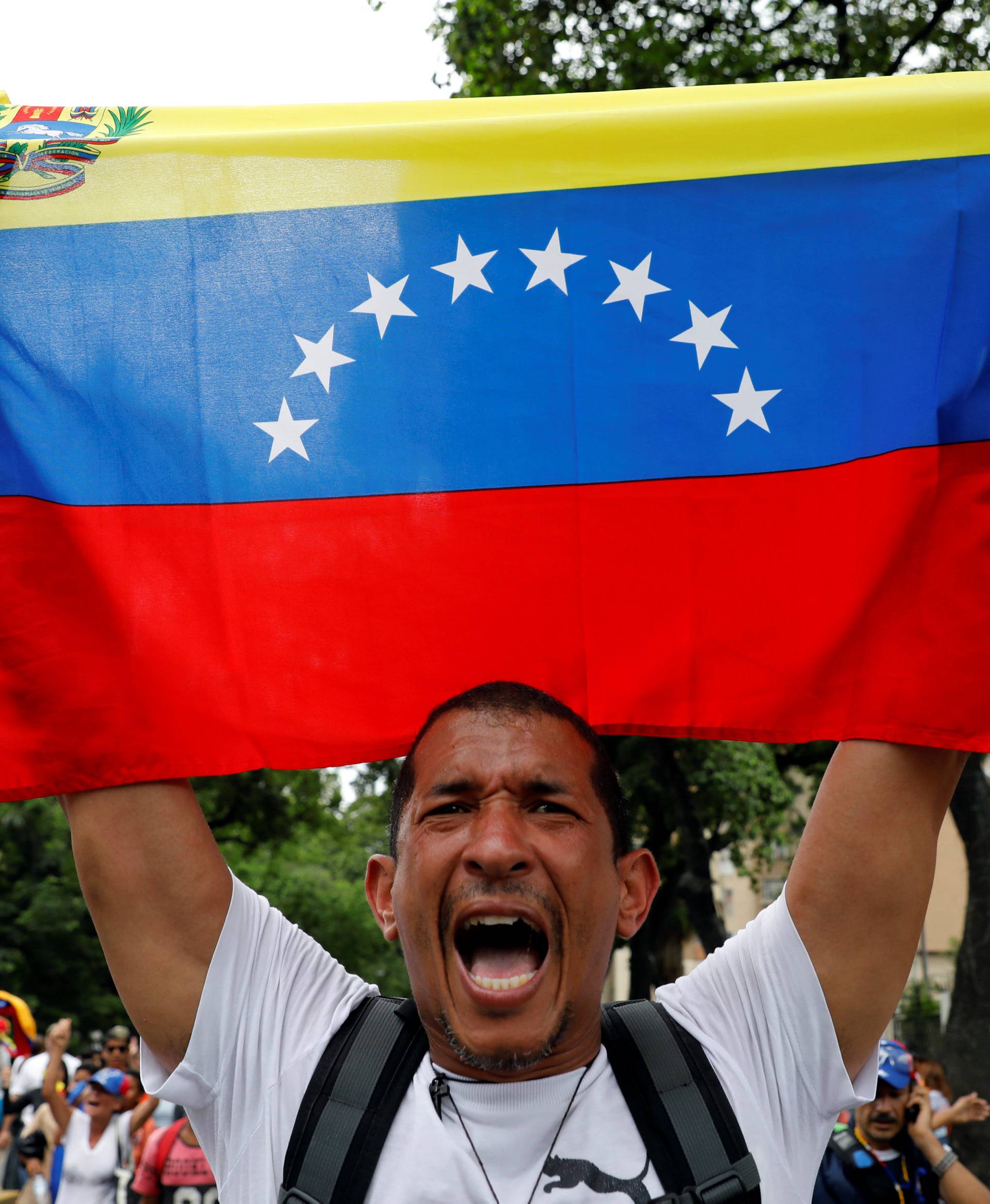 A demonstrator holds a Venezuelan flag as he takes part in a rally to honour victims of violence during a protest against Venezuela's President Nicolas Maduro's government in Caracas