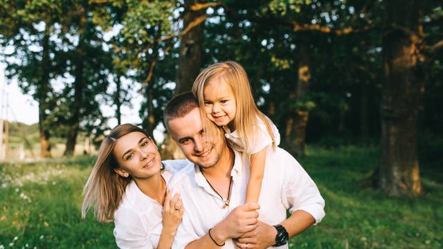 portrait of happy family looking at camera in forest on summer day