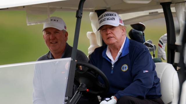U.S. President Donald Trump drives a golf cart at the Trump National Golf Club in Sterling