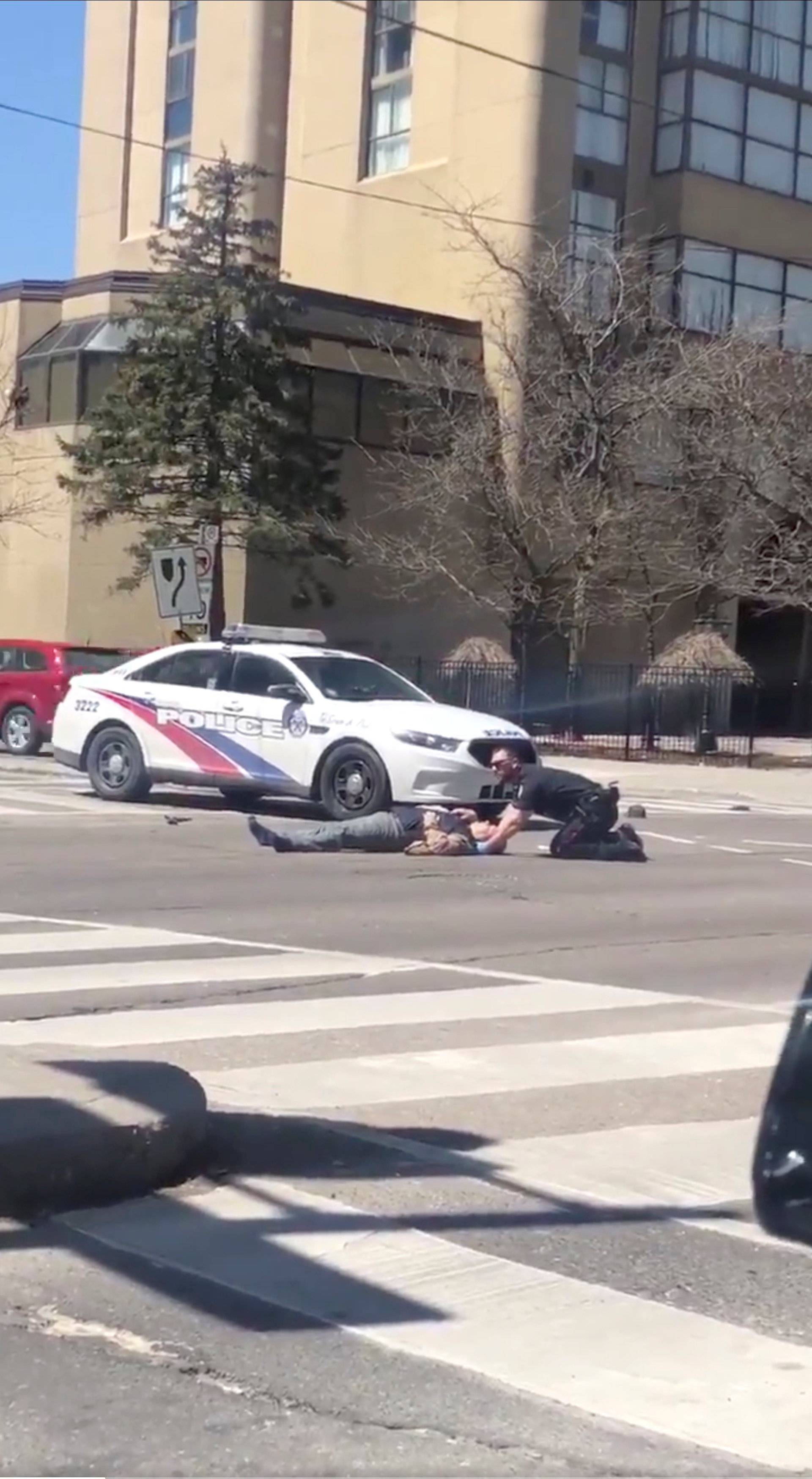 A victim is helped by police officer after a van hit multiple people at a major intersection in Toronto