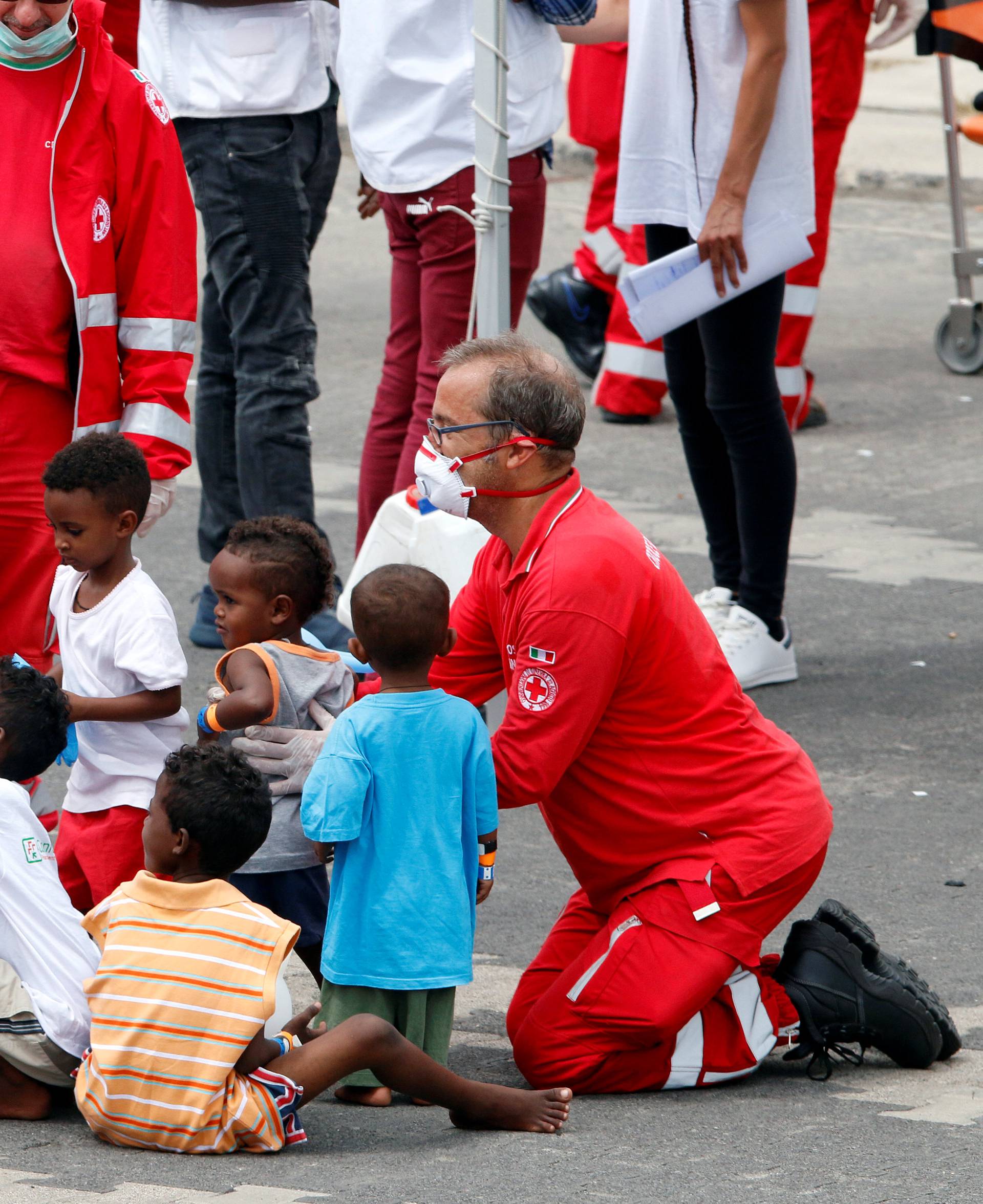 Italian Red Cross personnel play with children after they disembarked the Italian coast guard vessel "Diciotti" at the port of Catania