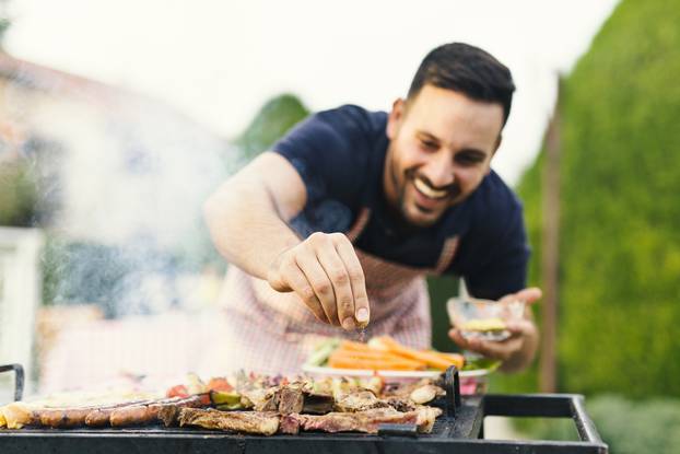 Smiling,Man,Seasoning,Meat,On,The,Grill