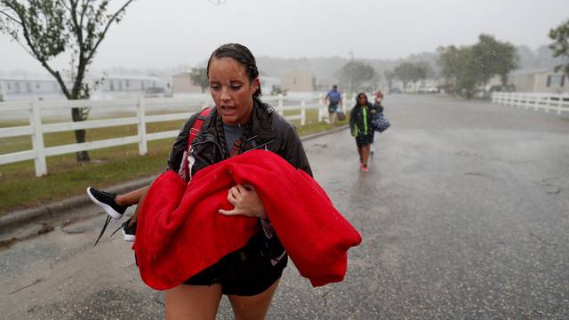During a driving rain, Maggie Belgie of The Cajun Navy, carries a child evacuating a flooding trailer community during Hurricane Florence in Lumberton